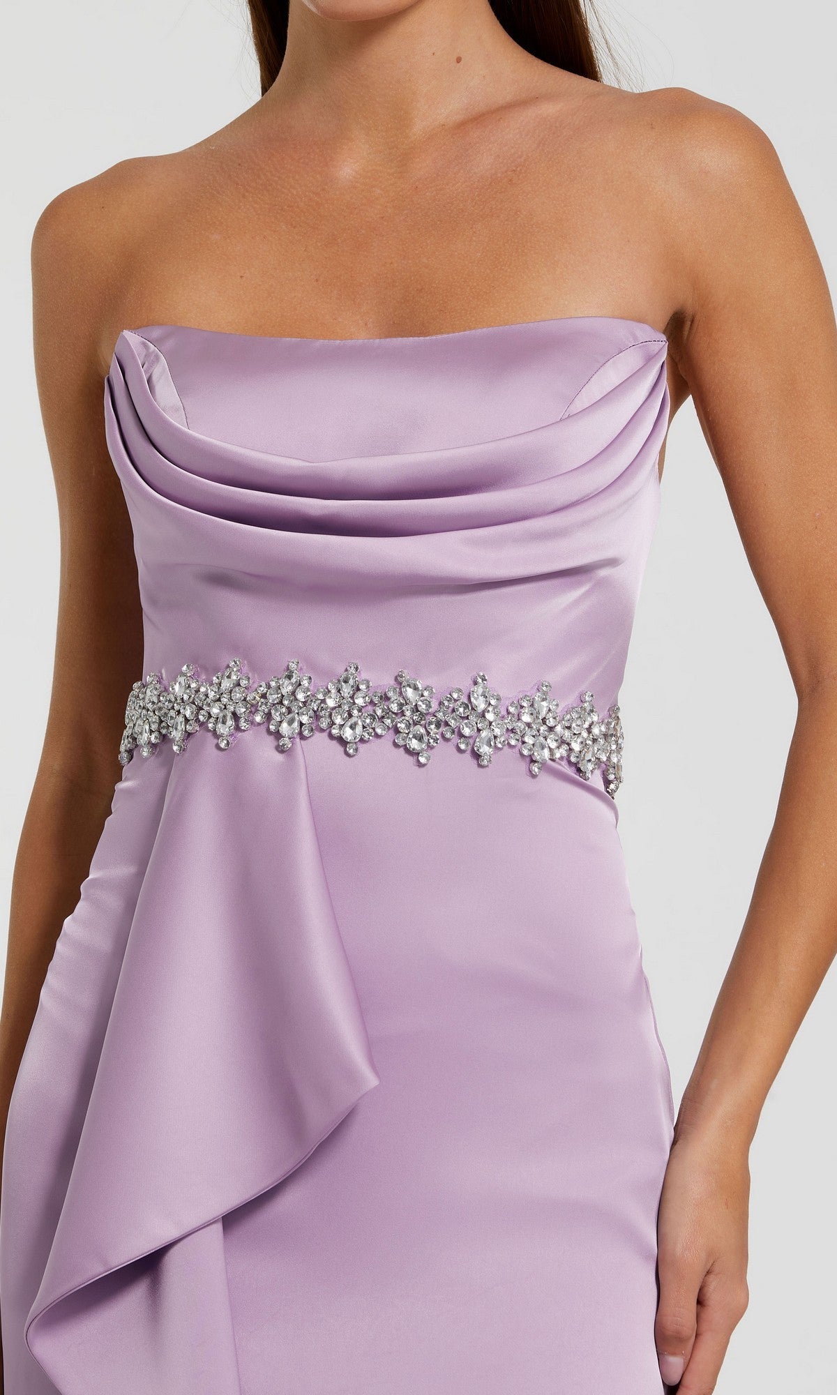 A woman wears the Mac Duggal 44133 long formal dress, a strapless lilac satin gown with a cowl neckline and an embellished floral belt at the waist.
